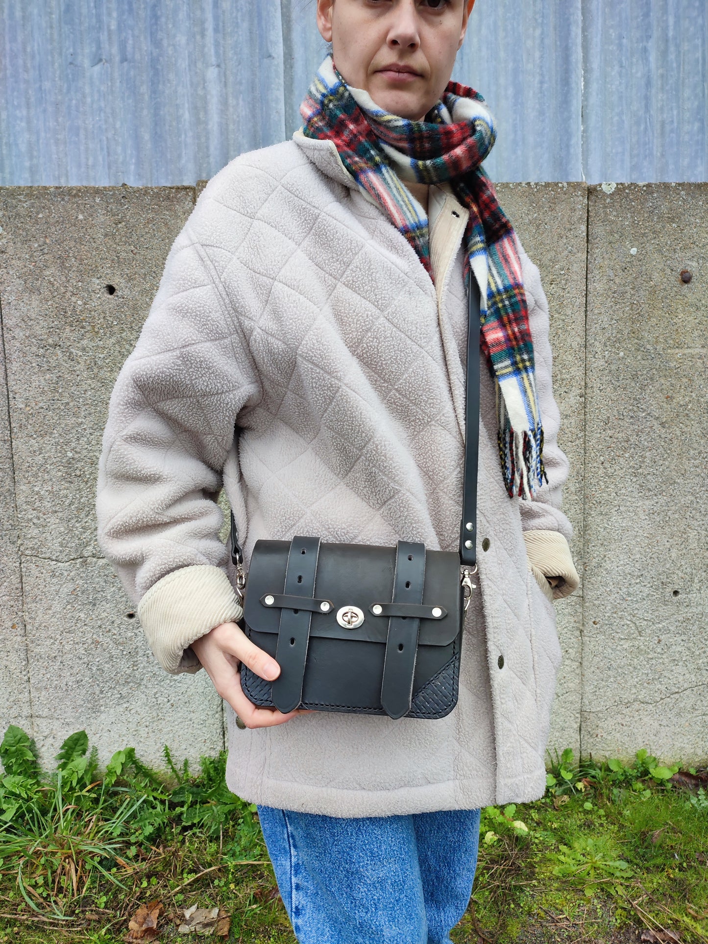 Le sac Besace style western noire possède un design passe partout avec des détails issus de l'équitation : les sanglons et la bandoulière en rêne de cheval.