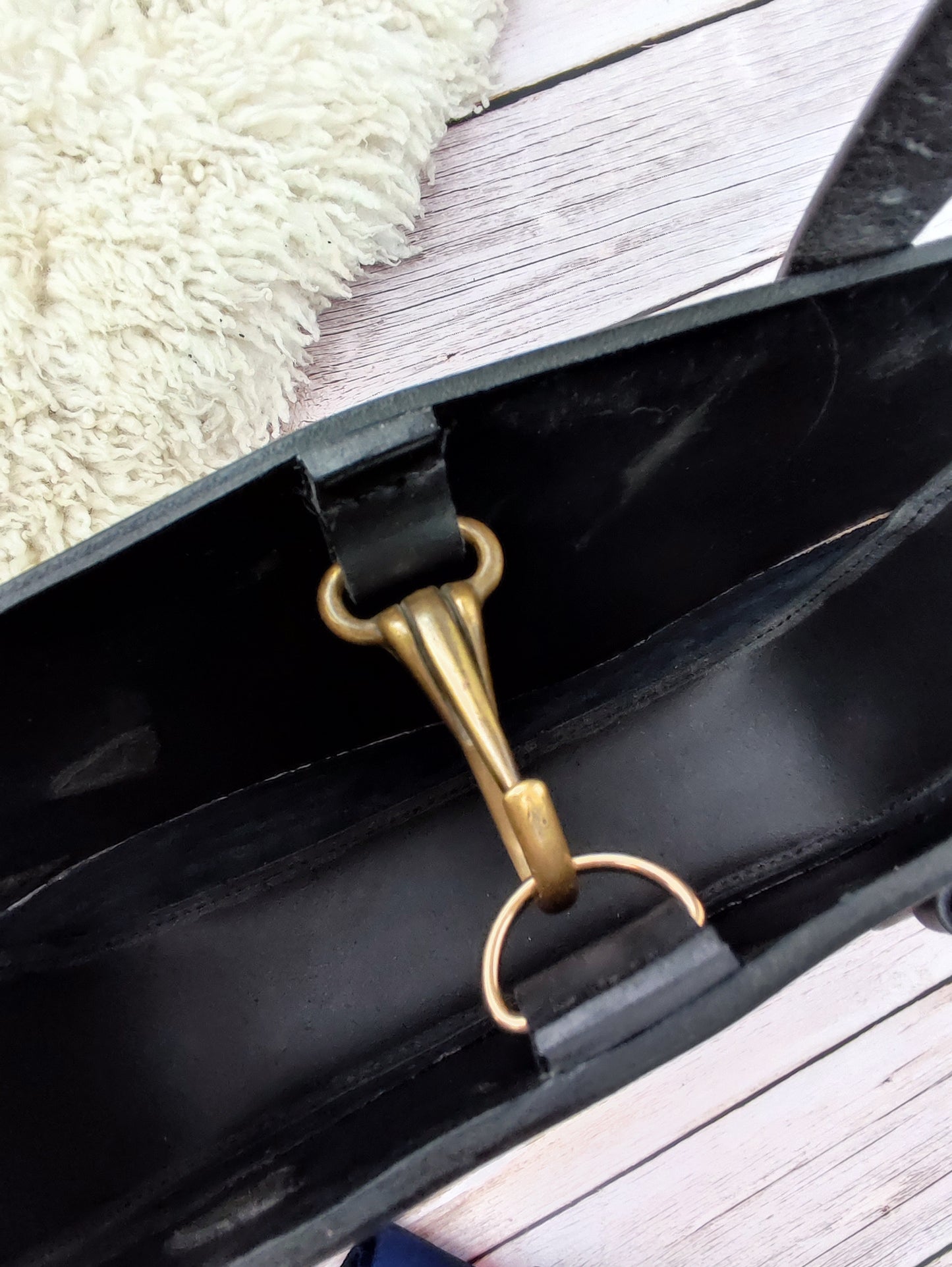 Vue en détail sur la fermeture du sac tote bag en cuir noir : un mousqueton récupéré sur un licol. L'intérieur du sac est laissé brut lui donnant un style rustique.