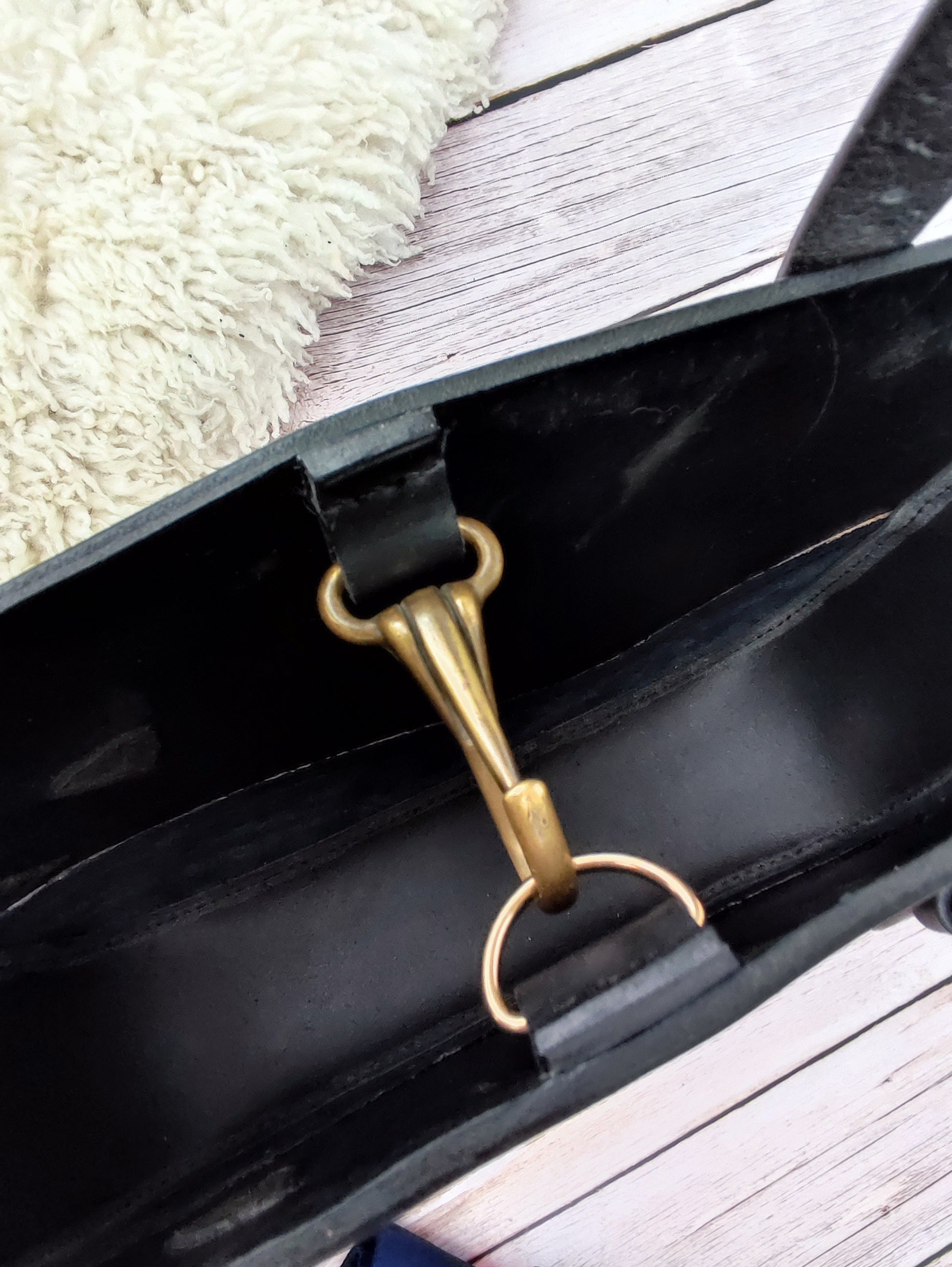 Vue en détail sur la fermeture du sac tote bag en cuir noir : un mousqueton récupéré sur un licol. L'intérieur du sac est laissé brut lui donnant un style rustique.
