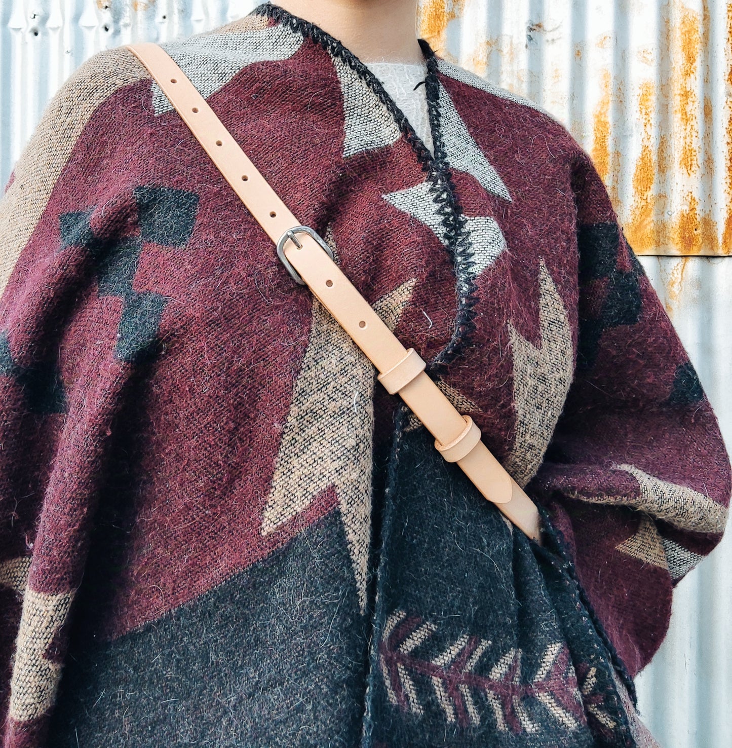 Vue en détails de la lanière en cuir de la banane porté sur un modèle avec un poncho motif aztèque.