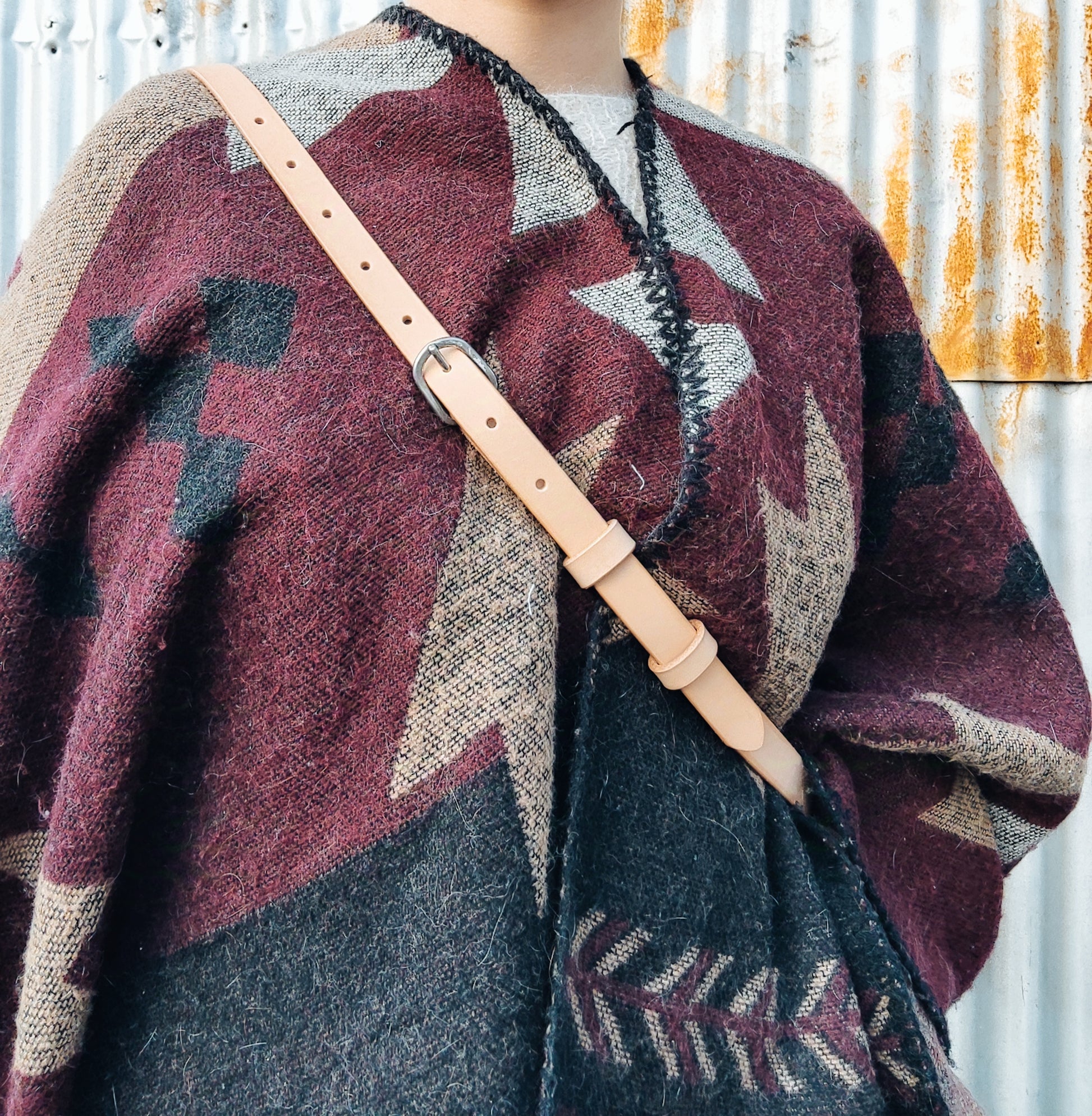 Vue en détails de la lanière en cuir de la banane porté sur un modèle avec un poncho motif aztèque.