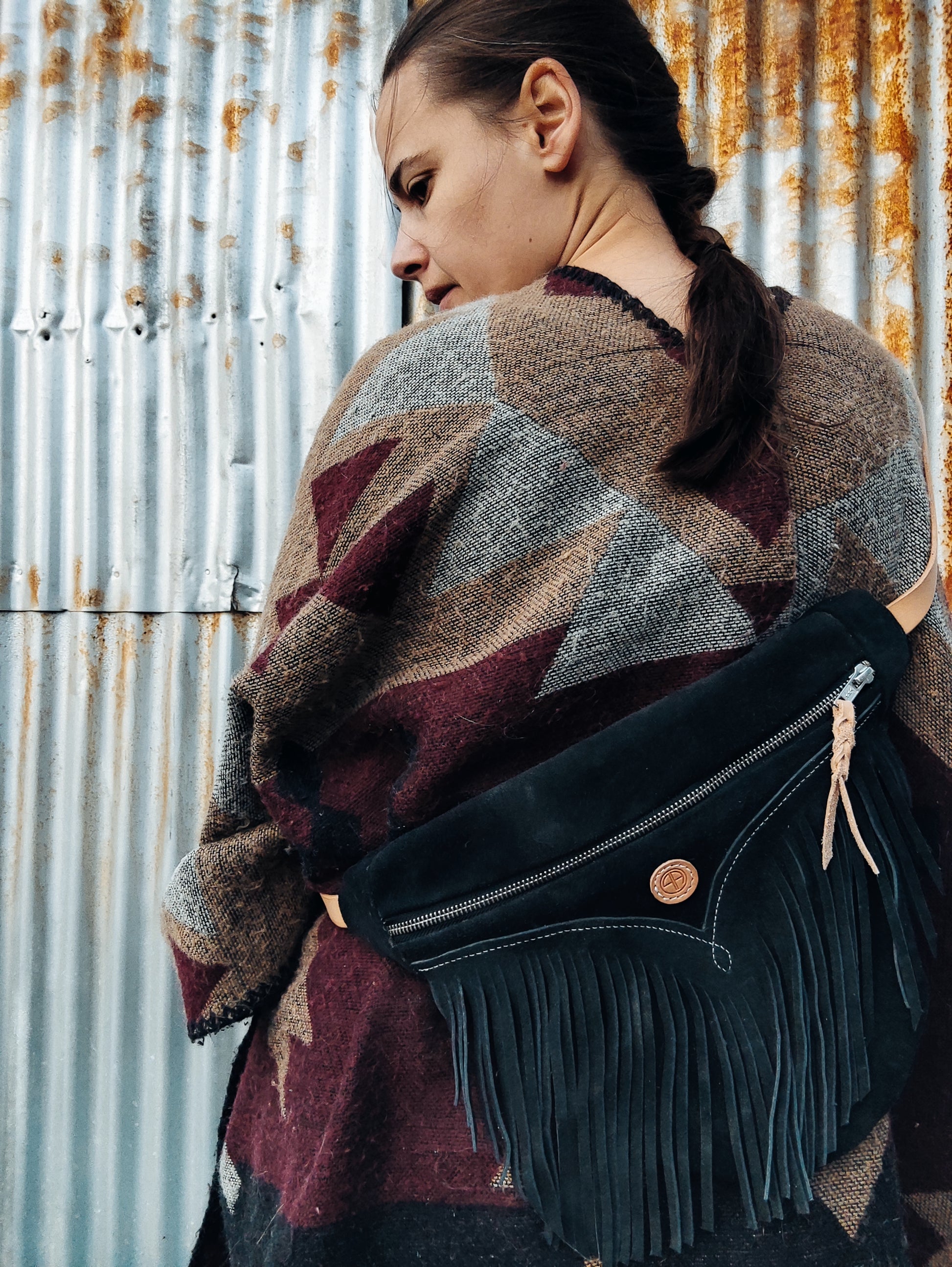 Cavalière de profil au style indien avec sac à franges noire en chaps recyclés.