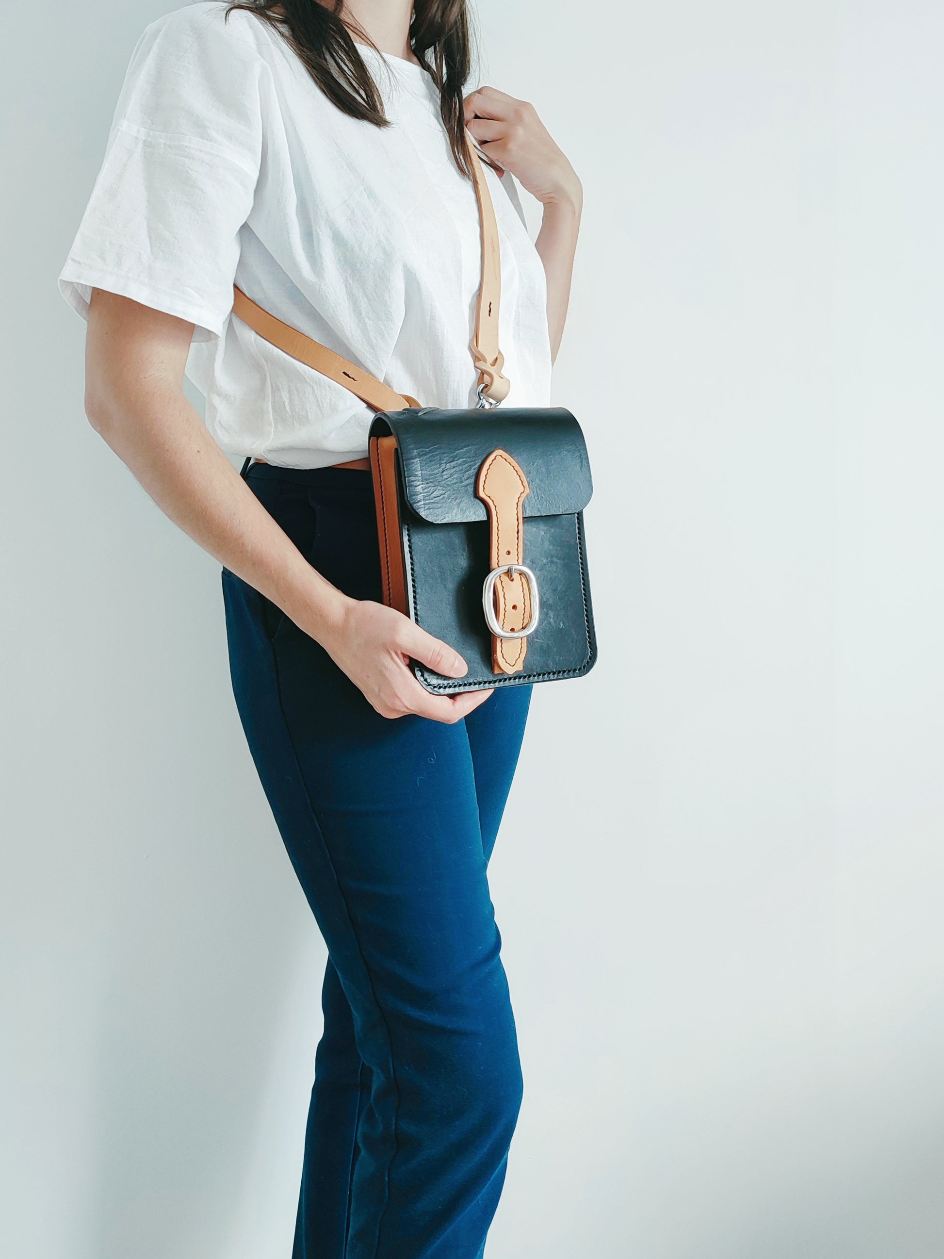 Le sac Grands Quartiers est porté en bandoulière. Il a un style unisexe et intemporel avec une fermeture par une boucle de licol.