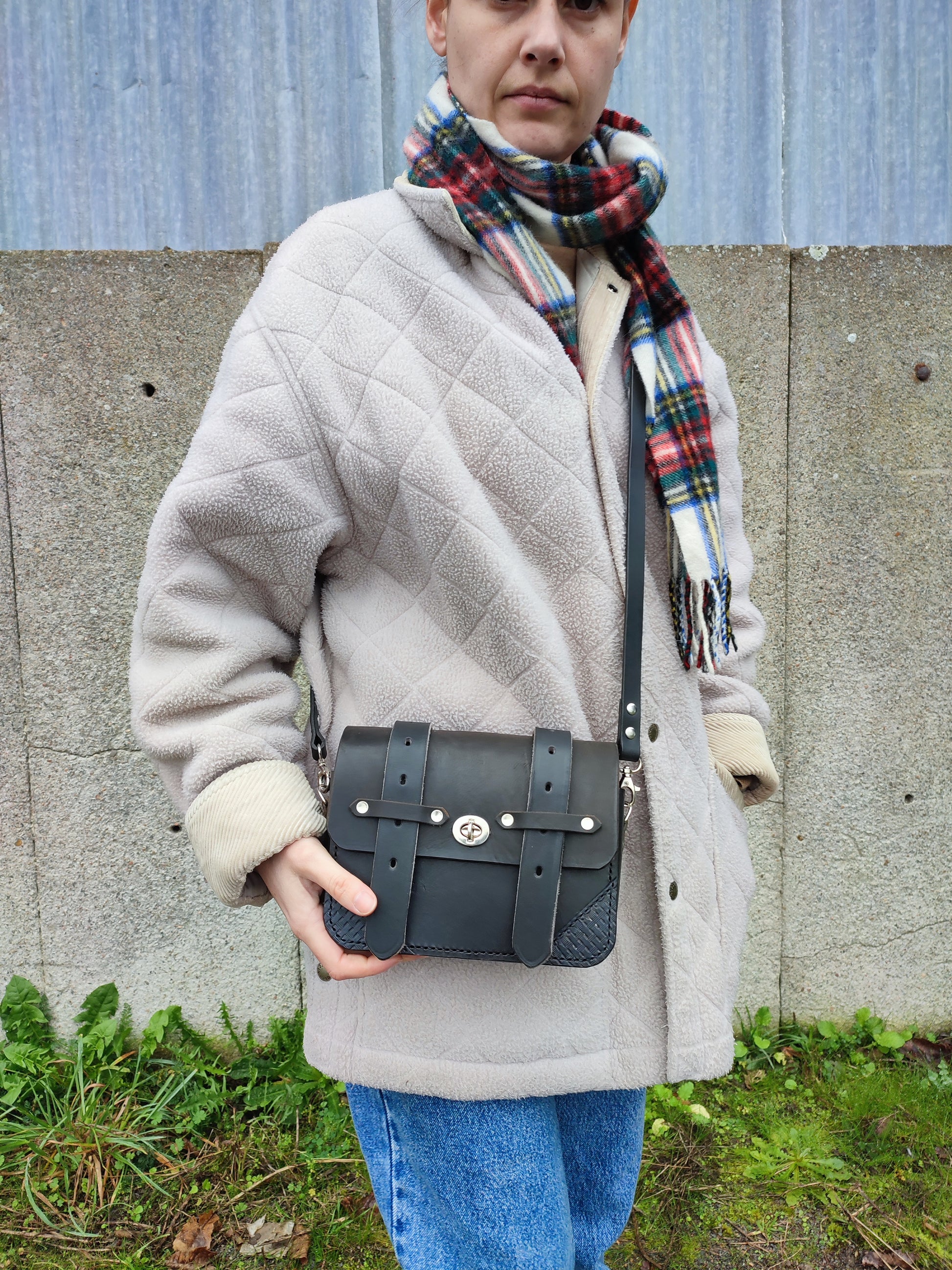 Le sac Besace style western noire possède un design passe partout avec des détails issus de l'équitation : les sanglons et la bandoulière en rêne de cheval.