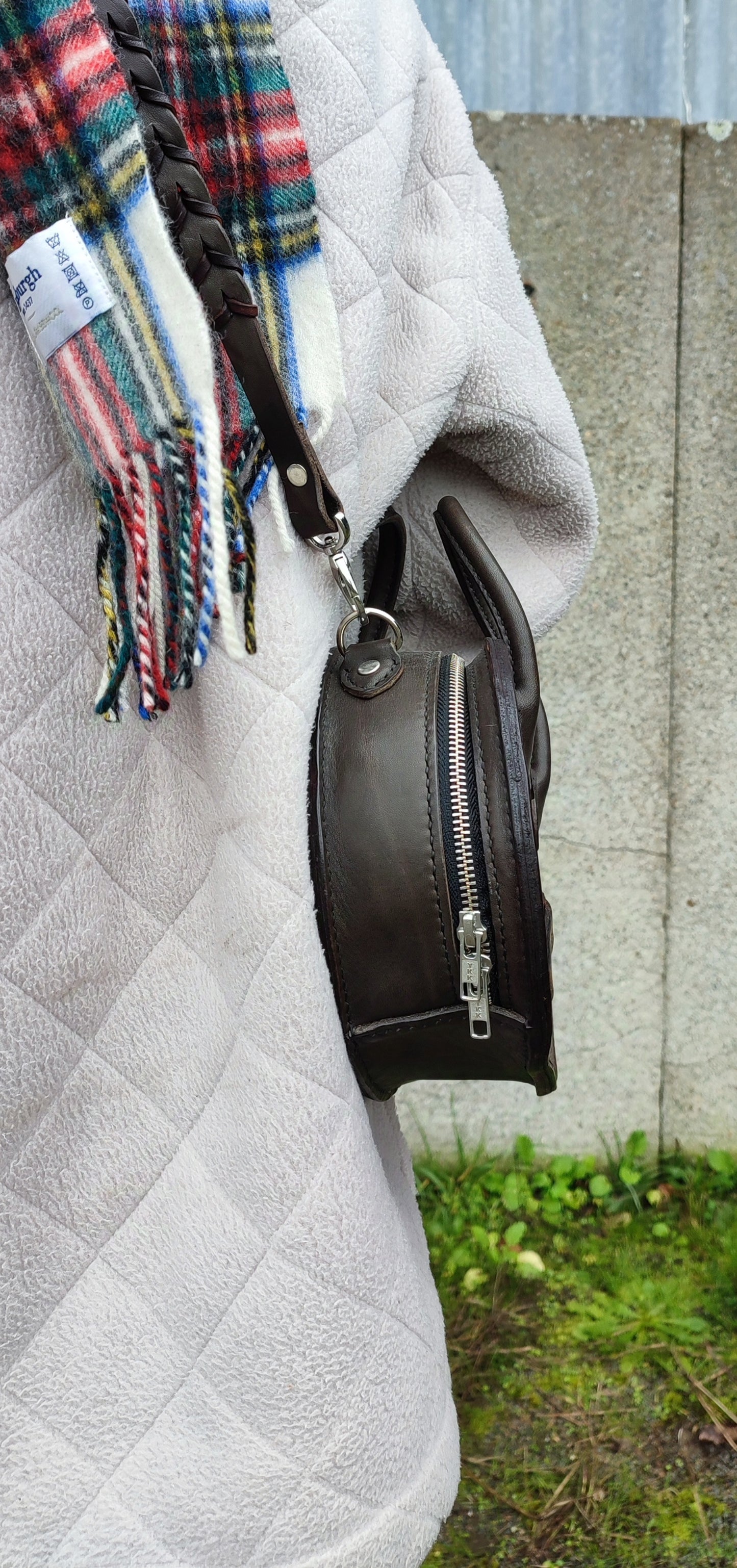 Détails du sac Oval qui se ferme avec une fermeture éclair sur tout son périmètre. Un sac rustique et chic.