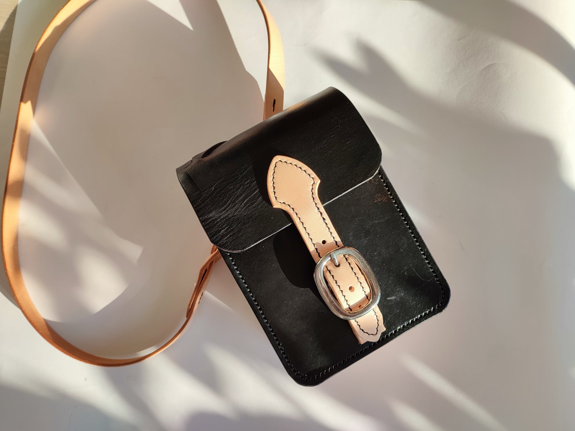 Jeux de lumière sur le sac Grands Quartiers mettant en évidence le cuir patiné de la selle qui offre un caractère unique et rempli d'histoire pour cet accessoire.