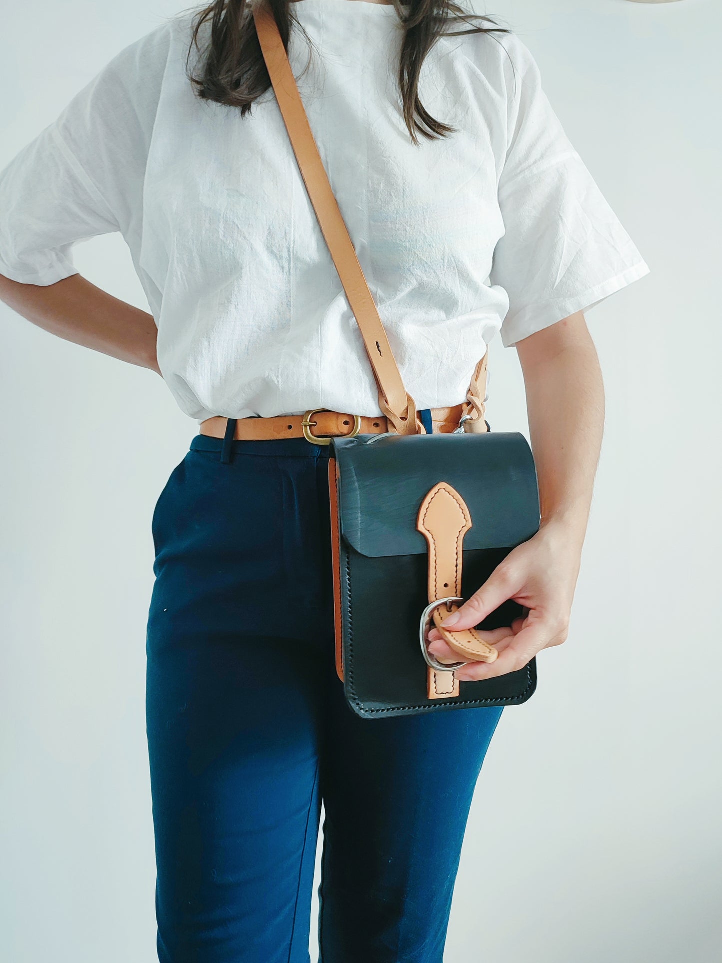 La sacoche grands quartiers est porté par une femme au style working girl qui détache la boucle de licol qui sert de fermeture.