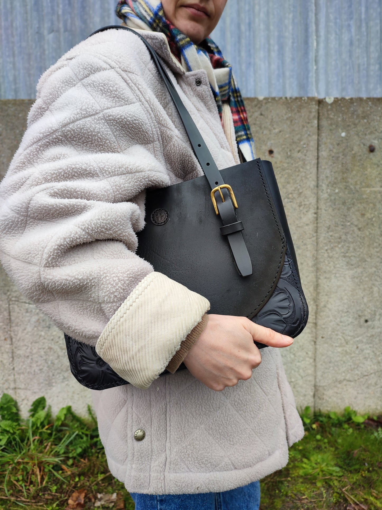 Le Tote bag est porté à l'épaule près du corps d'un manteau Aigle en polaire. On aperçoit le détail de la boucle de la anse récupérée sur un harais.